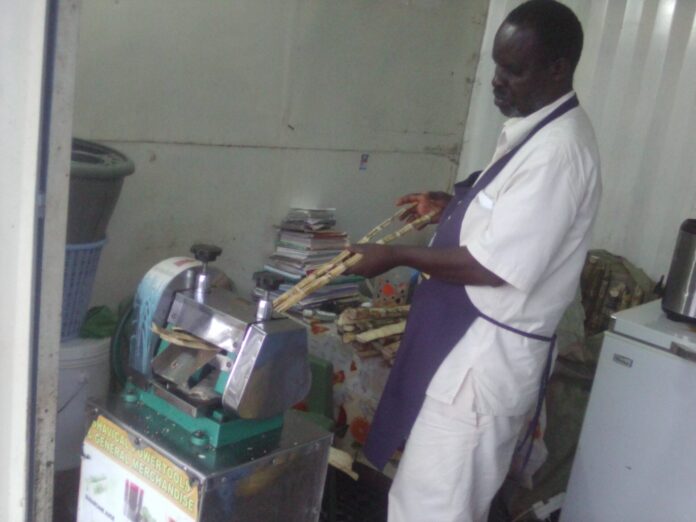 Michael Otieno Nyaguti. Founder and member of Magnam Environmental Network in Kisumu County is crushing sugarcane to produce Sugarcane juice at his Otonglo business premises. PHOTO/ Gilbert Ochieng.