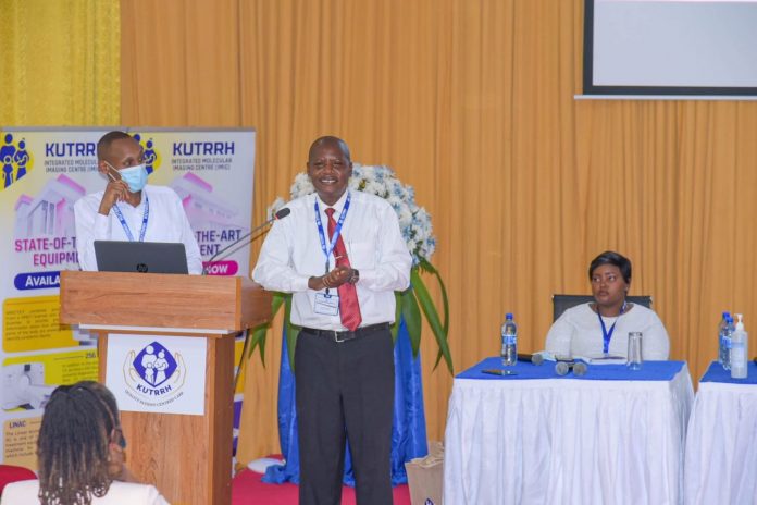 Evans Machera (center), a Nairobi-based city lawyer, addressing the First KUTRRH Annual Health Conference 2022 at the Kenyatta University Teaching, Referral & Research Hospital, two years after undergoing successful chemotherapy sessions at the health facility. PHOTO/Courtesy.