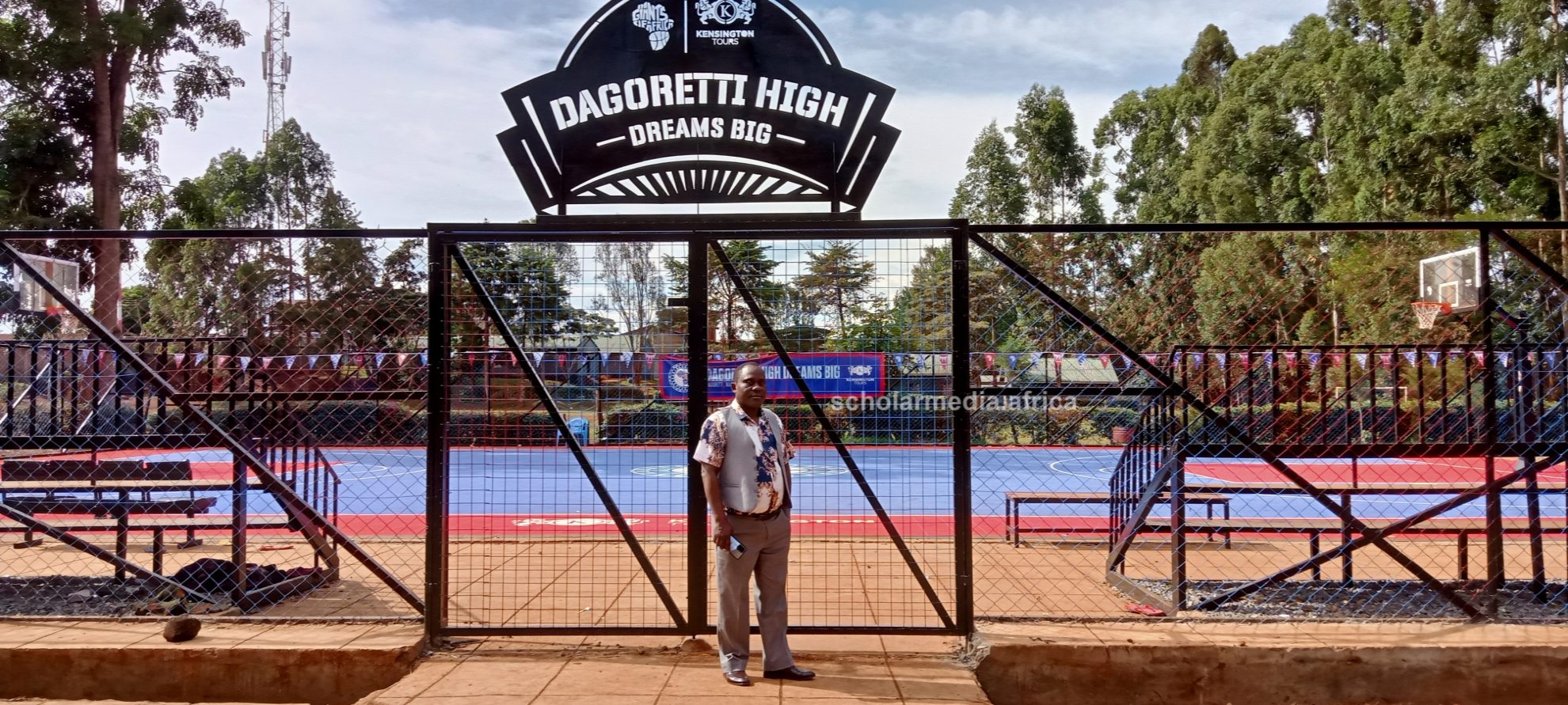 Chief Principal Nyakweba at the entrance to the new basketball court the school built recently, under his leadership. PHOTO/Tebby Otieno, Scholar Media Africa.