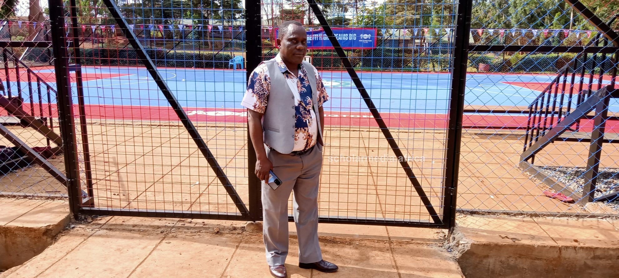 Mr. Nyakweba standing in-front of the basketball pitch. PHOTO/Tebby Otieno, Scholar Media Africa.