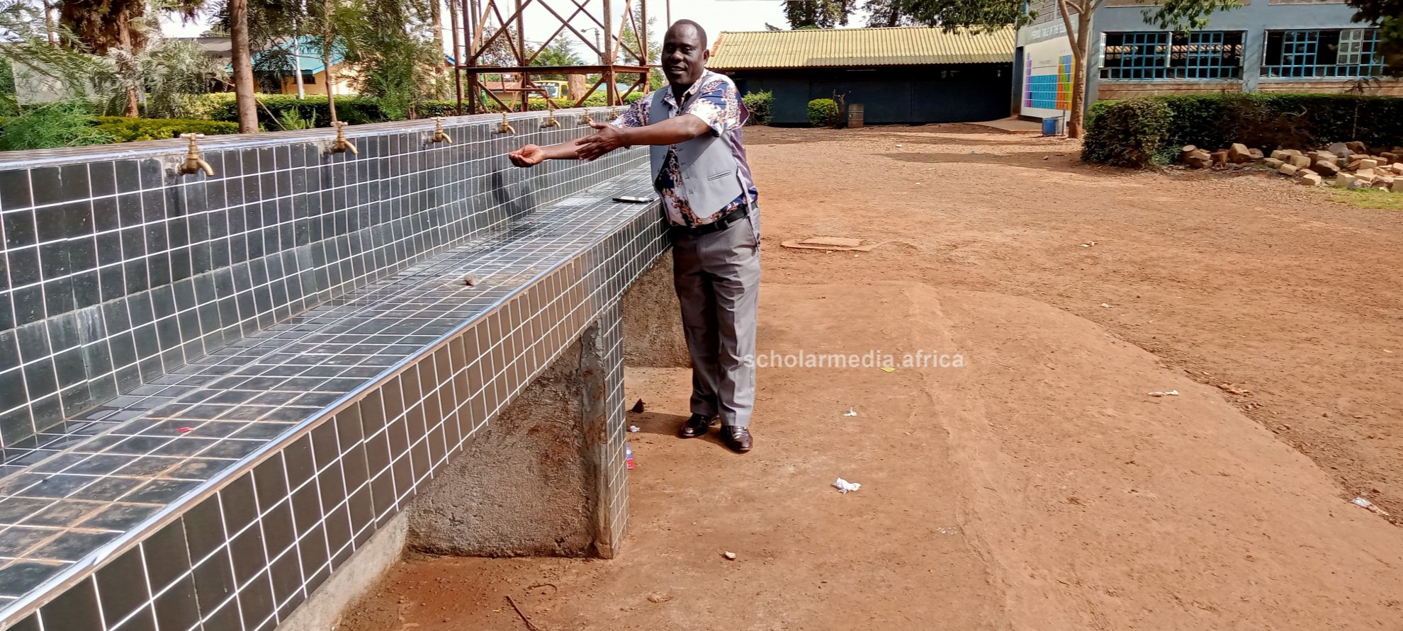 The chief principal at the institution's new washing area for students. PHOTO/Tebby Otieno, Scholar Media Africa.